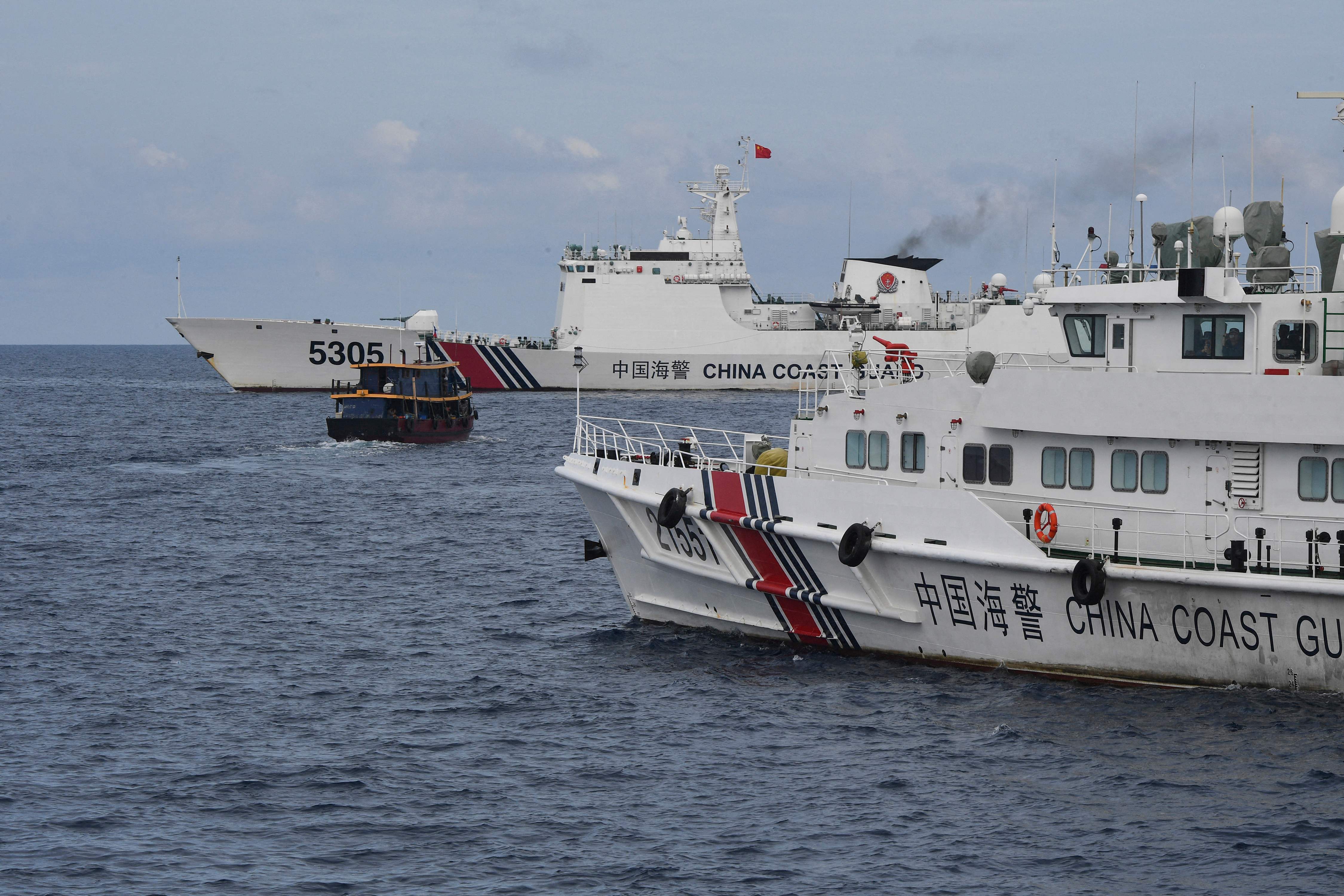 File Chinese coast guard ships (L and R) corralling a Philippine civilian boat chartered by the Philippine navy to deliver supplies to Philippine navy ship BRP Sierra Madre