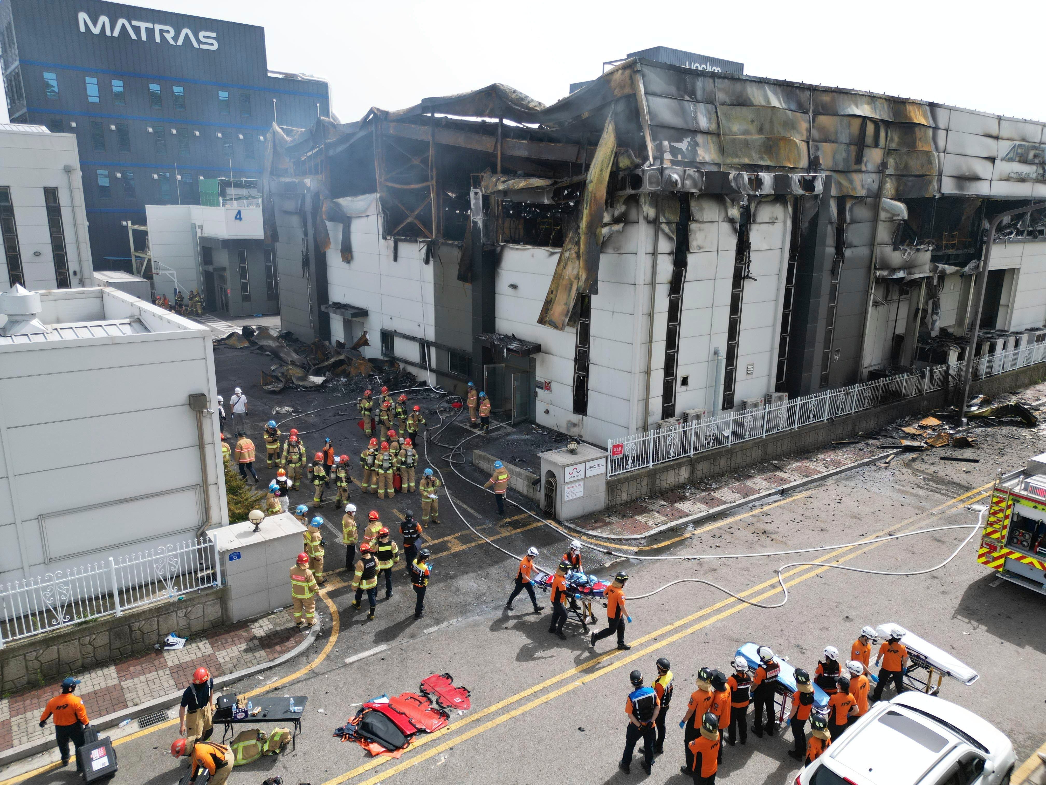 Firefighters carry a body at the site of a fire at a lithium battery manufacturing factory in Hwaseong