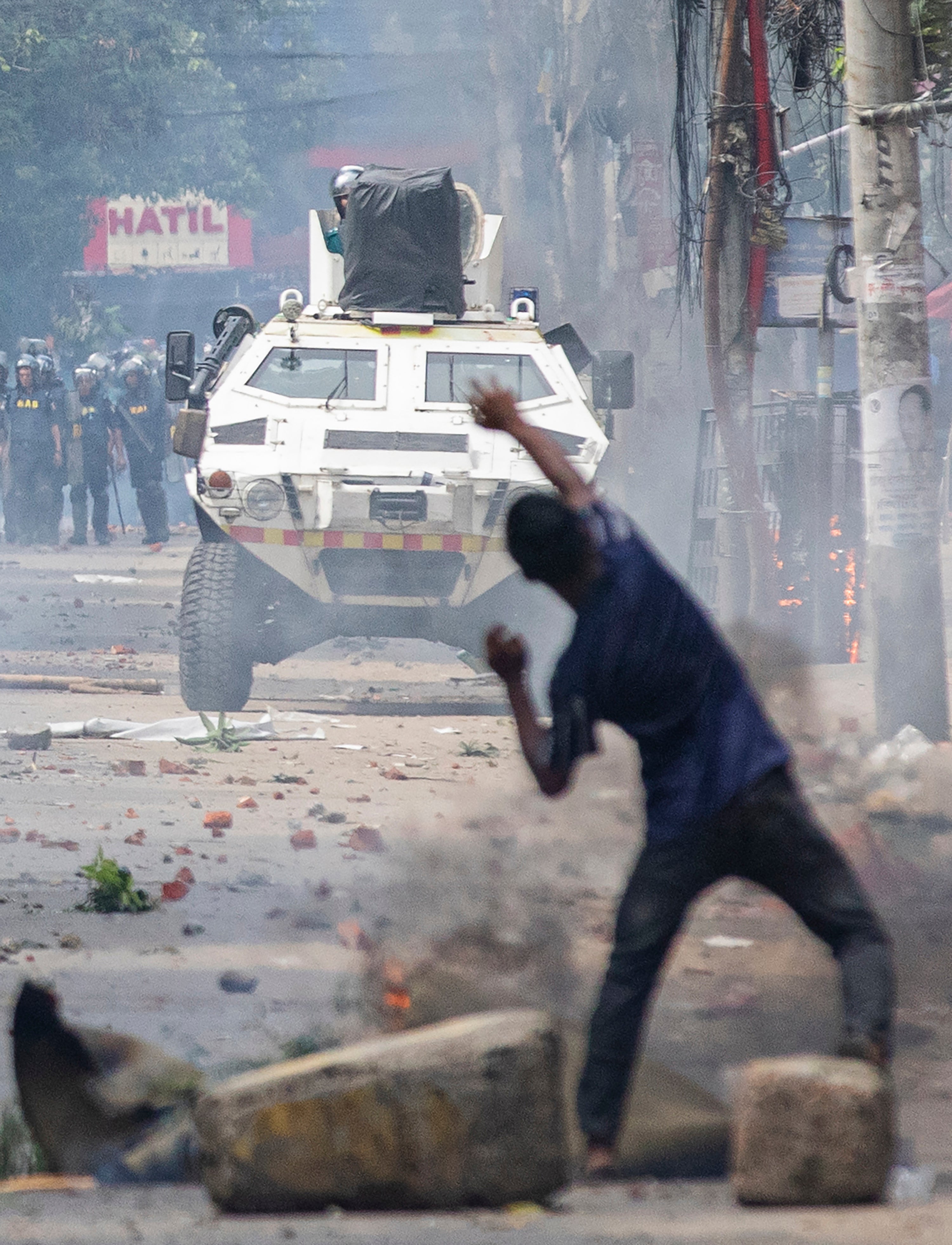 A student pelts stone towards an approaching armored police vehicle during protest over the quota system in public service, in Dhaka, Bangladesh