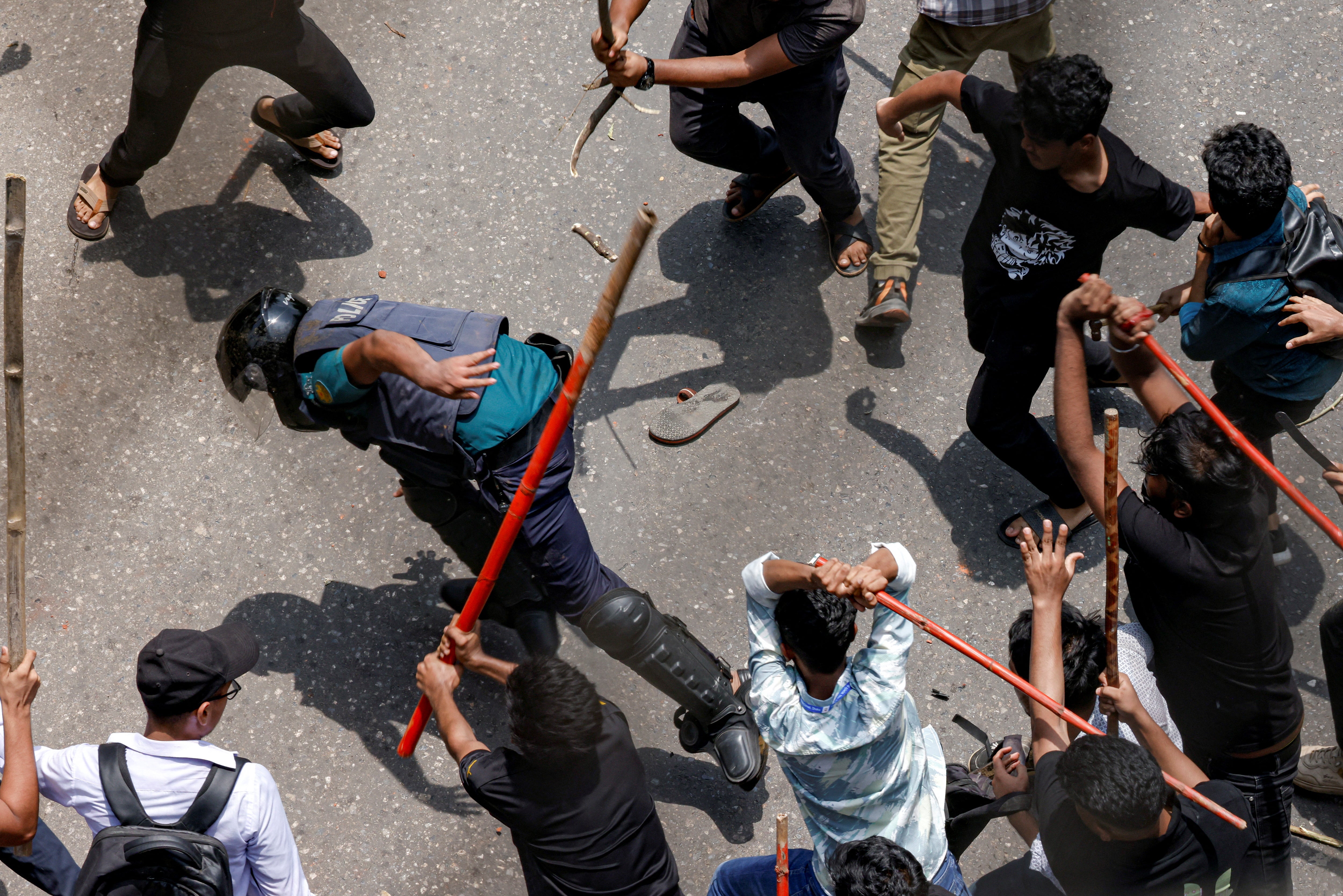 A police officer is beaten by mob during a clash between anti-quota supporters, police and Awami League supporters at the Rampura area in Dhaka