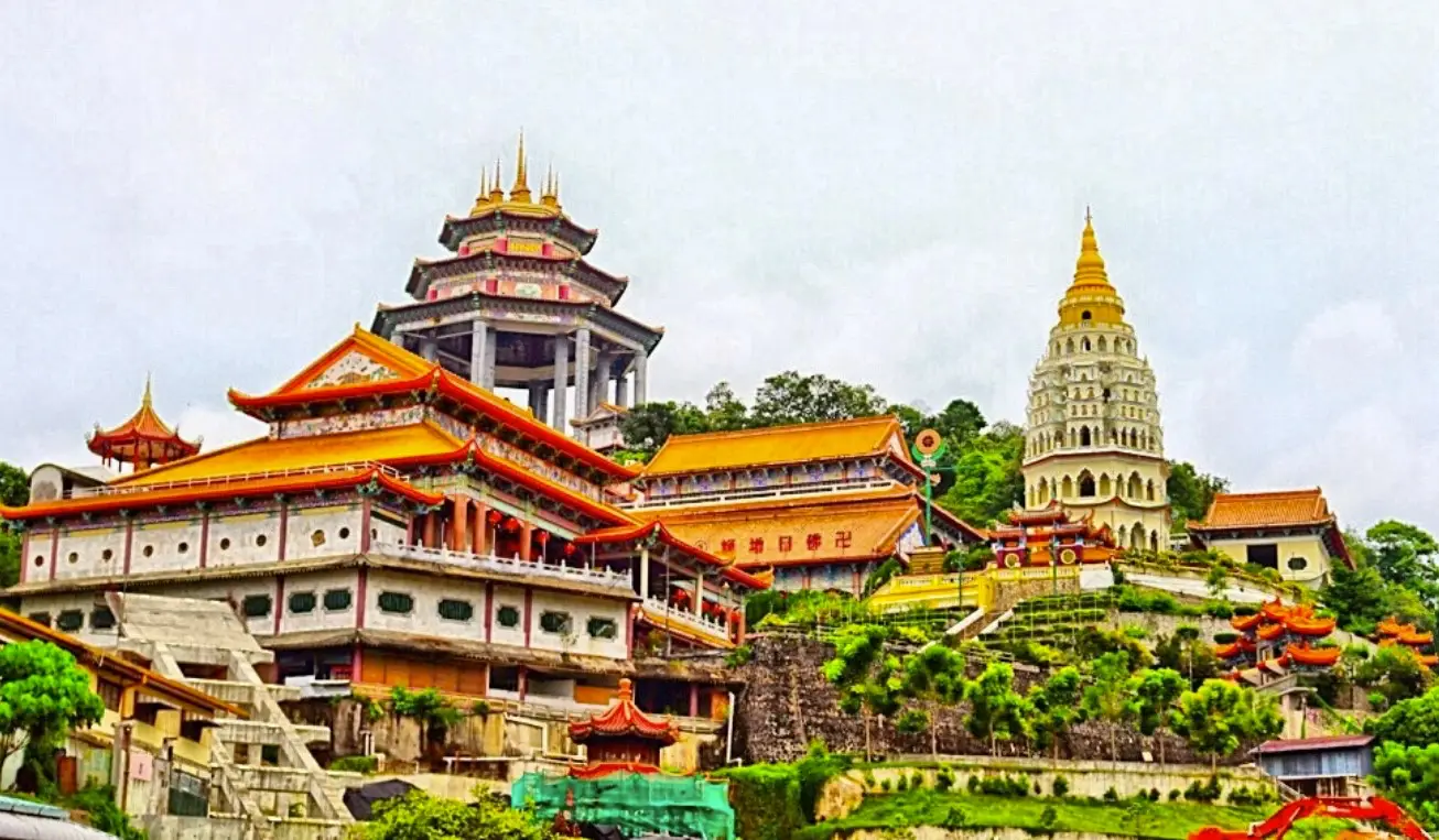 Kek Lok Si Temple in Penang, Malaysia, showcasing its sprawling complex of vibrant pagodas, prayer halls, and beautifully designed buildings set on a hillside. The temple is adorned with traditional Chinese architecture, featuring intricate carvings and colorful roofs.