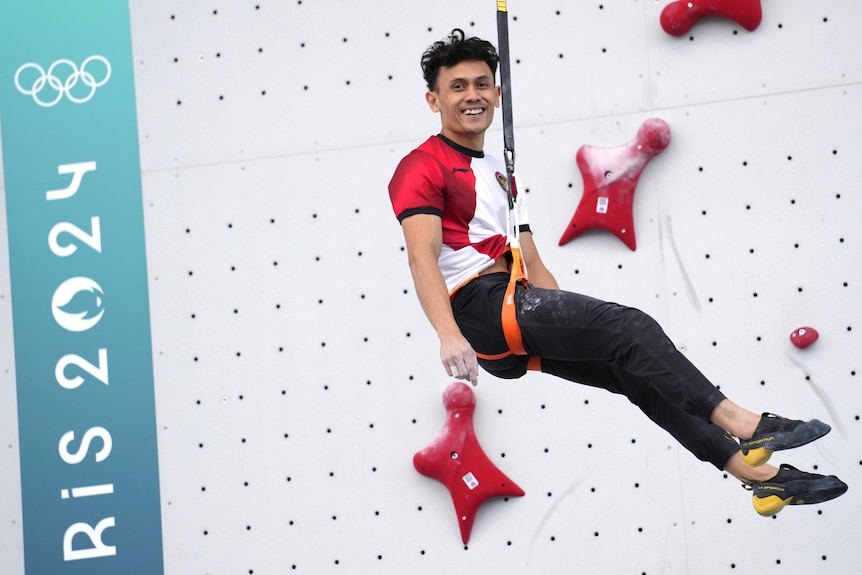 Veddriq Leonardo smiling in a harness after winning speed climbing event at the Olympics.