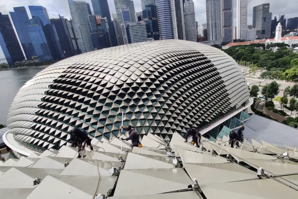 Aerial view of the Esplanade – Theatres on the Bay in Singapore, featuring its distinctive durian-like dome with maintenance workers cleaning the sunshade panels.