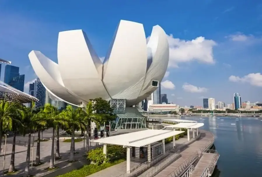 Exterior view of the ArtScience Museum in Singapore, featuring its iconic lotus flower-shaped design with the city skyline and Marina Bay in the background.