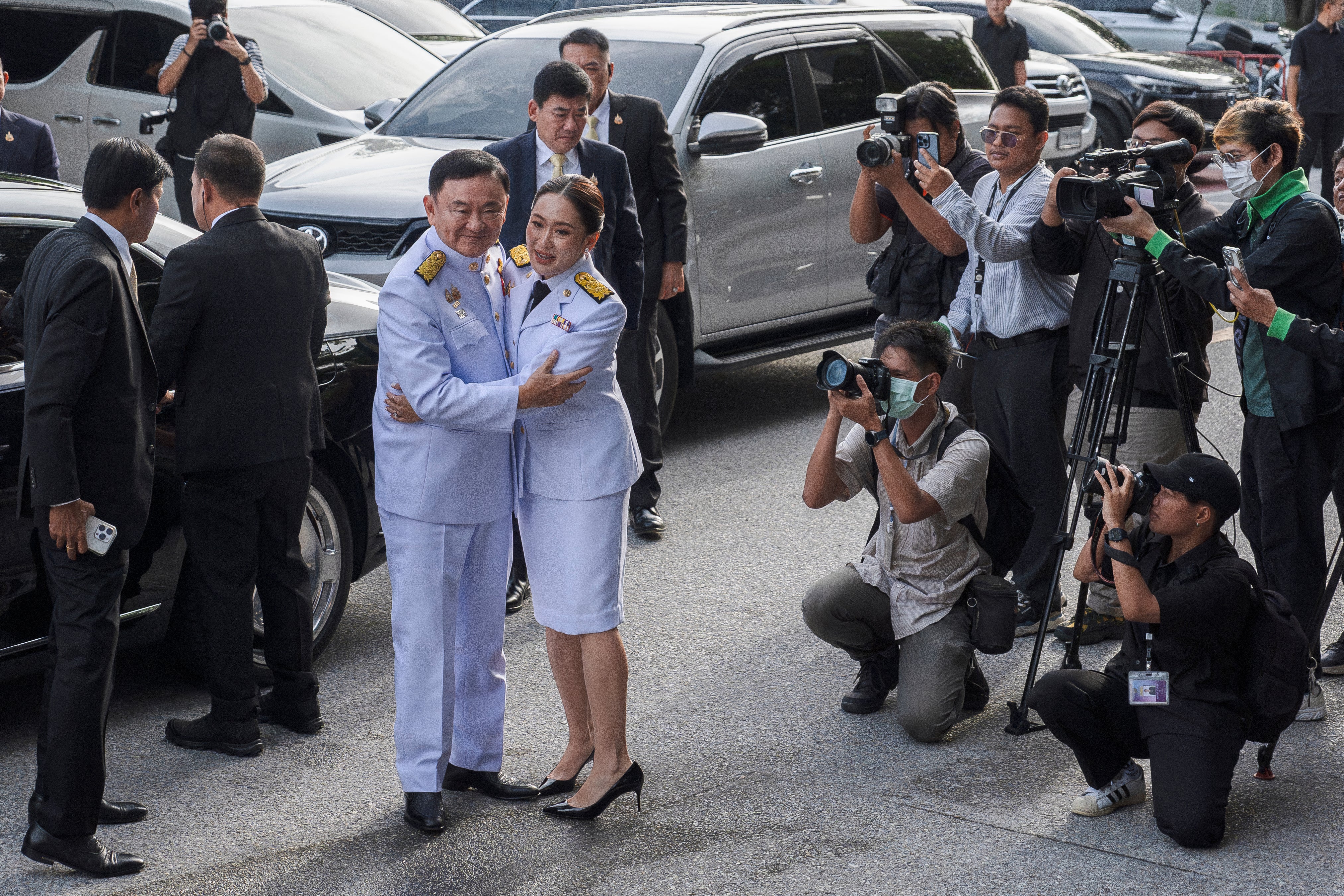 Paetongtarn Shinawatra embraces her father, former prime minister Thaksin Shinawatra, as they arrive for the royal endorsement ceremony