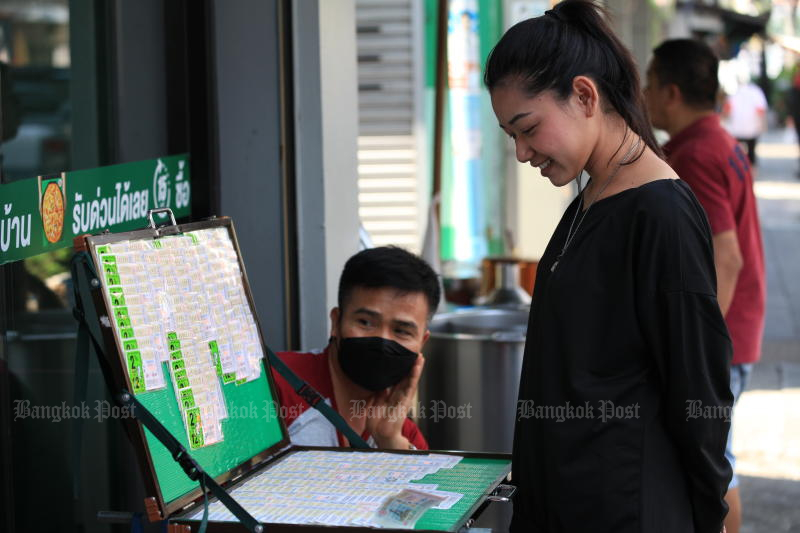 A woman examines lottery tickets on sale near Ratchabophit temple in Phra Nakhon district, Bangkok. Thailand is a Buddhist nation where gambling does not align with Buddhist precepts. (Photo: Apichart Jinakul)