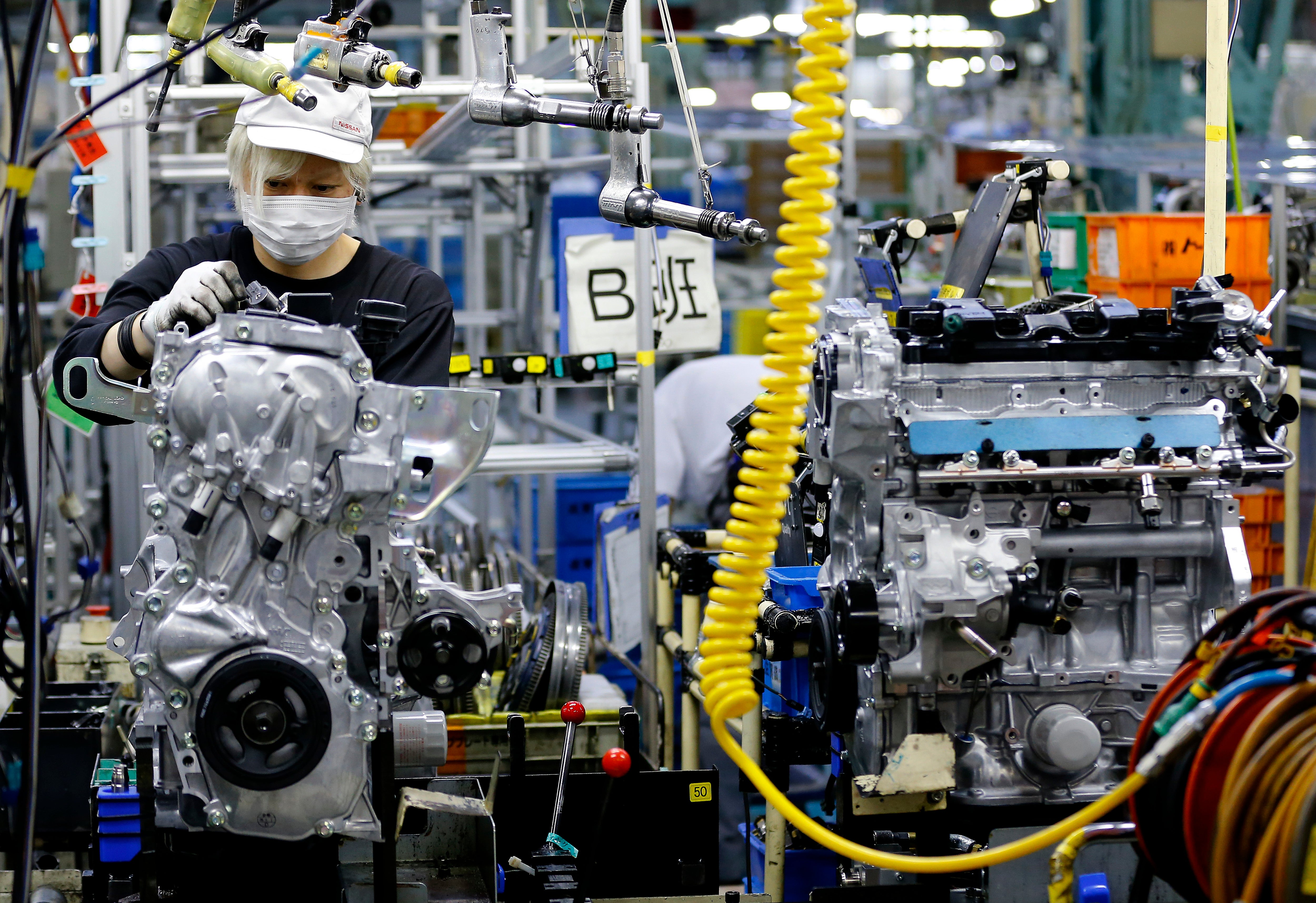 A Nissan Motor Co. factory worker checks an engine on an assembly line at its plant in Yokohama, near Tokyo