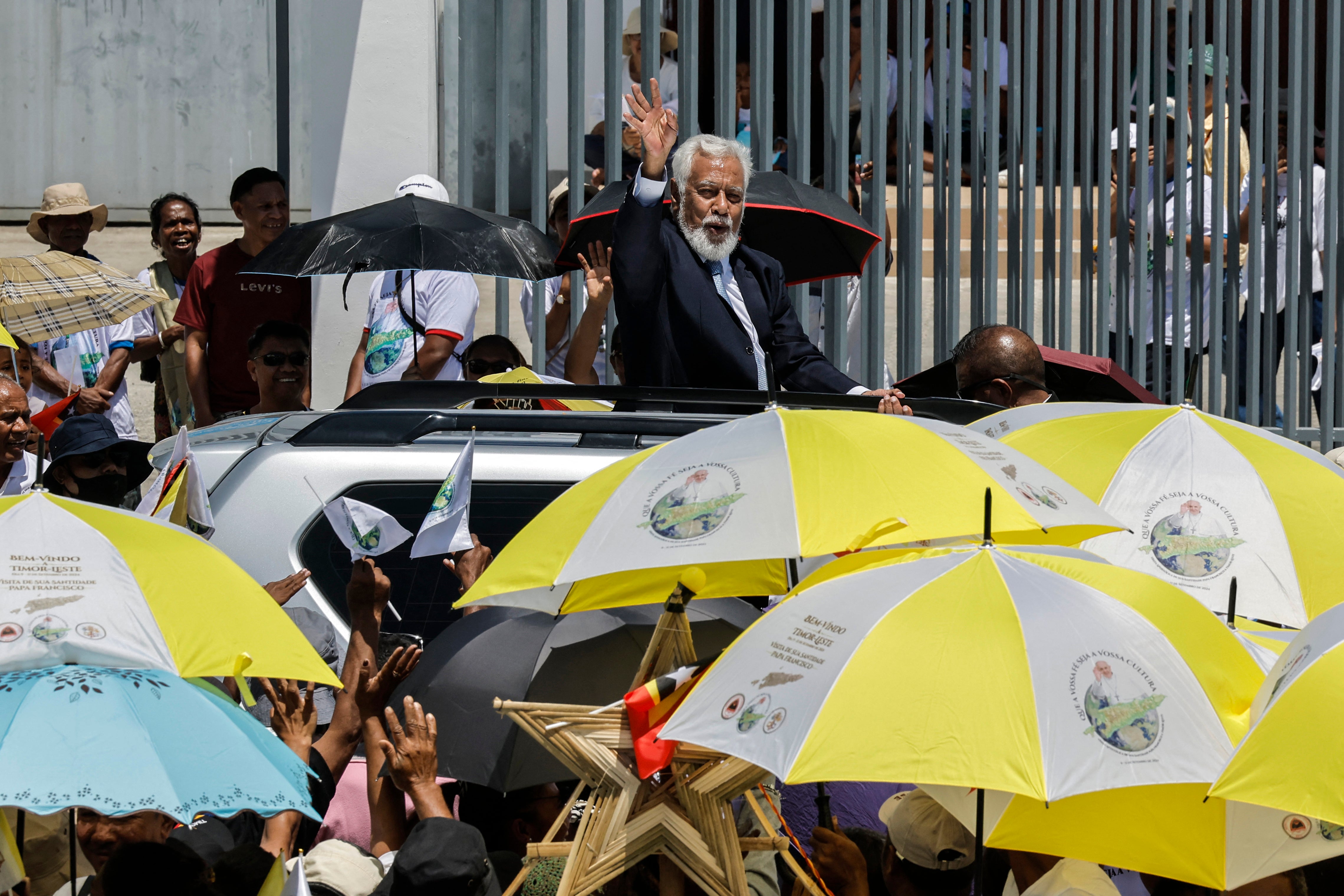 East Timor’s Prime Minister Xanana Gusmao waves to Catholic faithful lining the street as he travels to the airport to meet Pope Francis in Dili on September 9