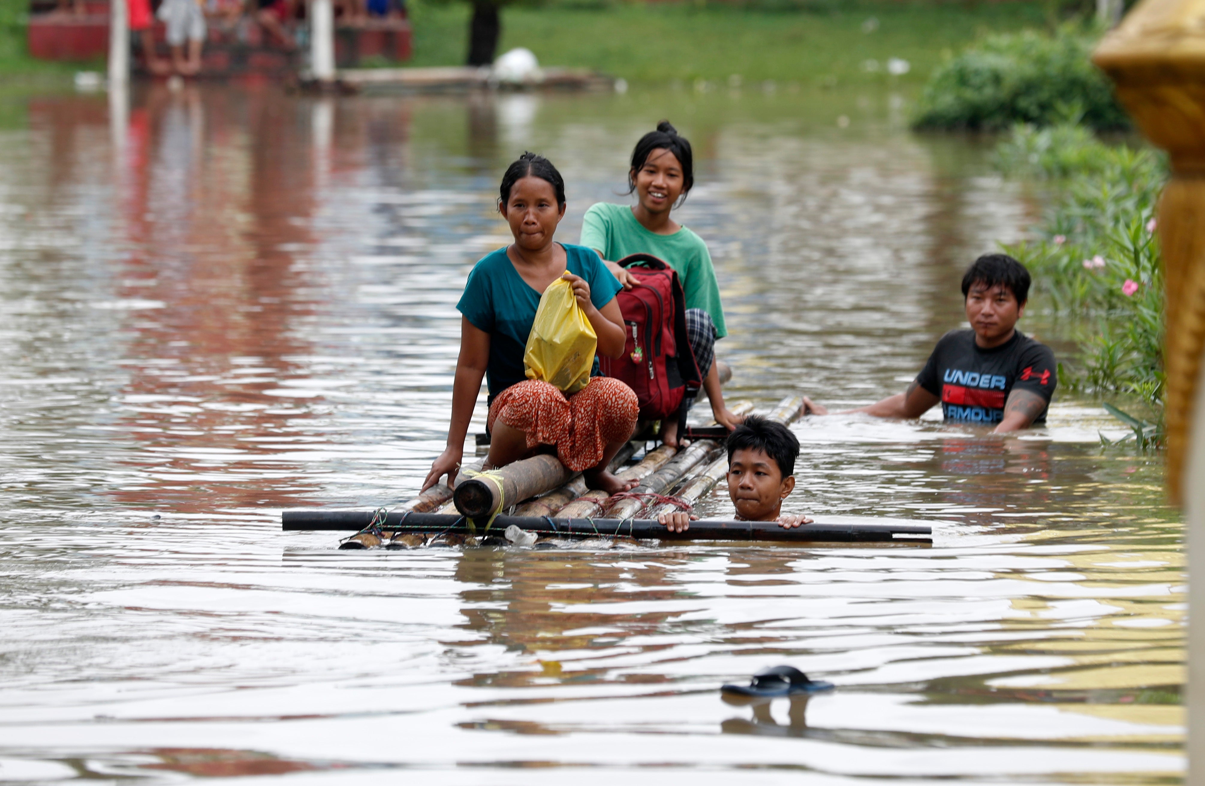 Flood victims wade through the flood waters with a makeshift raft during the flood in Taungo