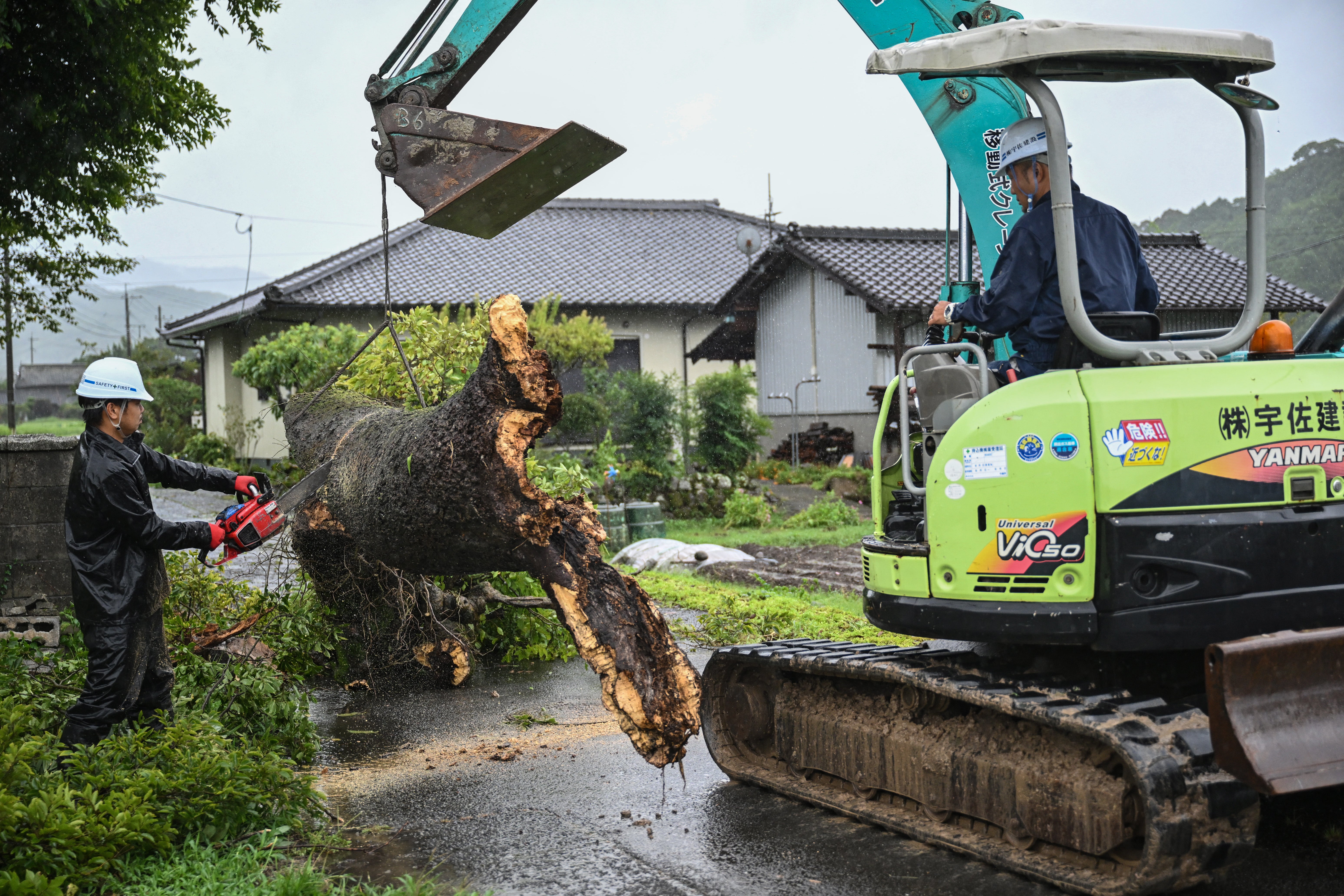 Workers remove a fallen tree brought down by strong winds in Usa, Oita prefecture