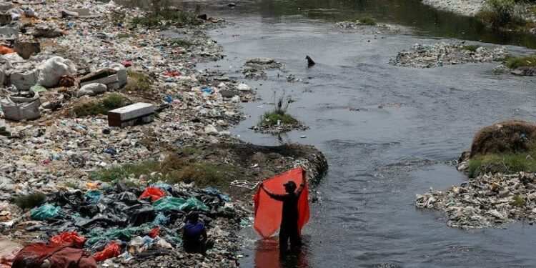 a man washes waste plastic sheets collected for recycling in the polluted waters on world environment day in karachi pakistan june 5 2023 photo reuters